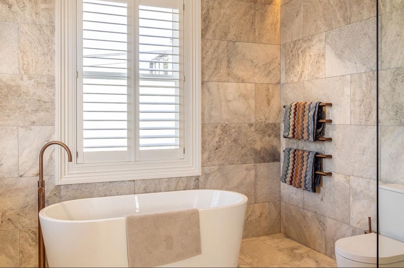Elegant bathroom with natural stone tile walls, freestanding bathtub, and custom tiling work