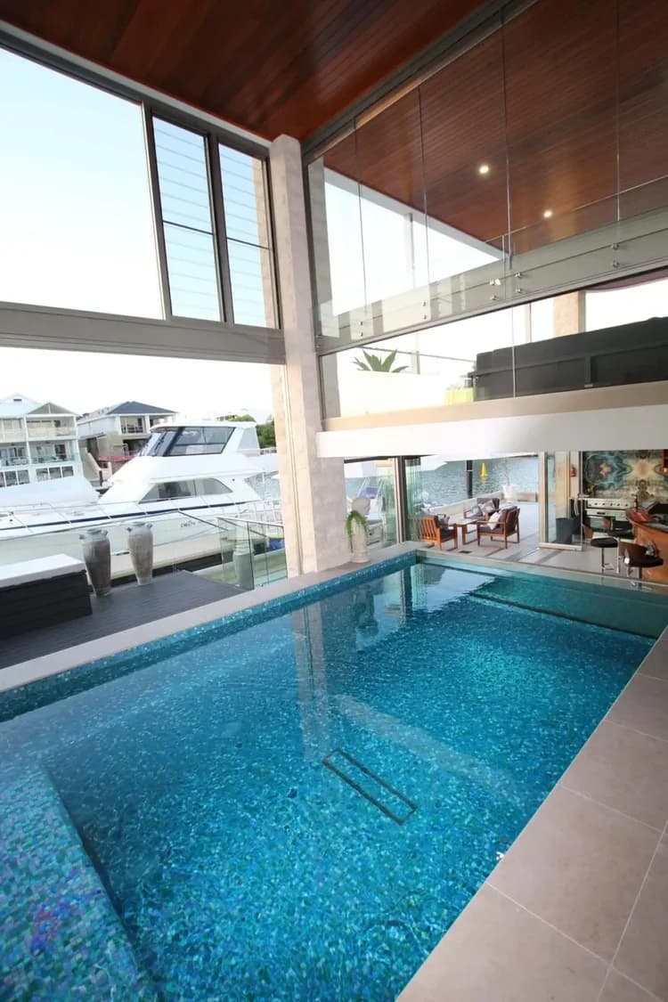 Luxury indoor pool with turquoise mosaic tiles and floor-to-ceiling windows